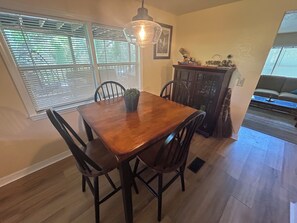A dining area with a wooden table and chairs, a potted plant, and a hanging light fixture.