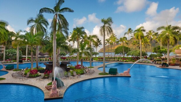A large outdoor swimming pool with multiple lanes, surrounded by palm trees and lounge chairs. - 1 BR Ocean Front at Marriott Kauai (Kauai)