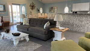 A modern living room with a grey sectional sofa, a white coffee table, and a patterned rug.