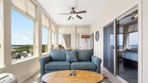 Une pièce avec un canapé bleu, une table basse en bois et un ventilateur de plafond.