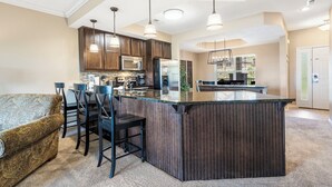Une cuisine moderne avec des meubles en bois foncé, des appareils électroménagers en acier inoxydable et un îlot central.