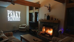 Una sala de estar acogedora con chimenea, asientos cómodos y una amplia pantalla de televisión.