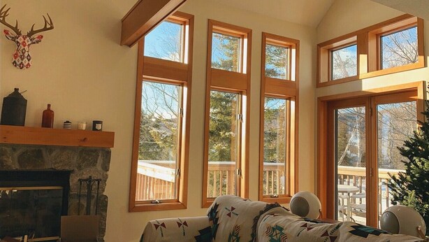 Una habitación acogedora con chimenea, una cama y grandes ventanales que ofrecen vistas al exterior.