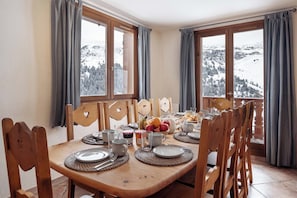 A dining area with a wooden table set for four, surrounded by chairs with heart-shaped cutouts.