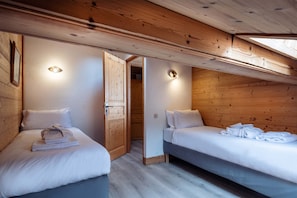 A room with two beds, wooden walls, and ceiling lights.