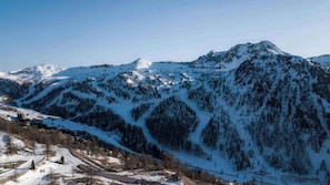 Paesaggio montuoso con pendii innevati e una stazione sciistica.