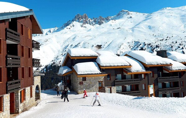 Un complejo turístico en la montaña cubierto de nieve, con edificios de madera y pistas de esquí.
