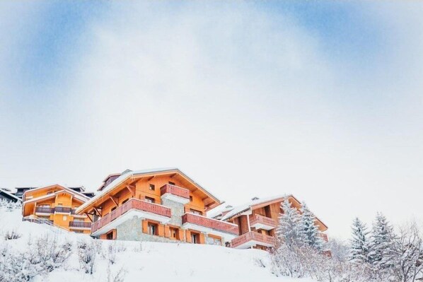 Un hotel a più piani con balconi in legno e un paesaggio innevato.