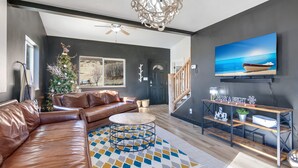 Een moderne woonkamer met een leren bank, een ronde salontafel, een houten tv-meubel en een groot schilderij van een boot aan de muur.