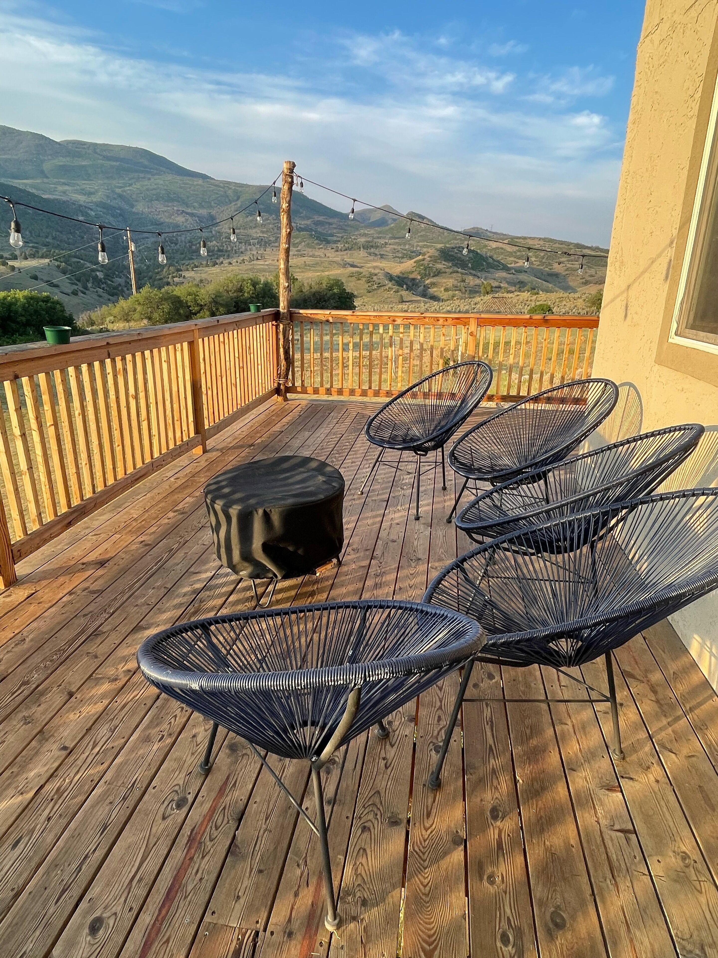 A wooden deck with outdoor seating, a table, and a view of a mountainous landscape.