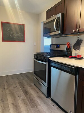 A kitchen with a stove, oven, microwave, and dishwasher. There is a chalkboard with "Welcome" written on it.