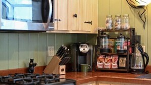 Uma cozinha com armários de madeira, micro-ondas, cafeteira e diversos utensílios.