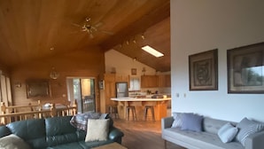 Ein geräumiges Wohnzimmer mit Holzbalkendecke, einem Essbereich und einer Küche im Hintergrund.