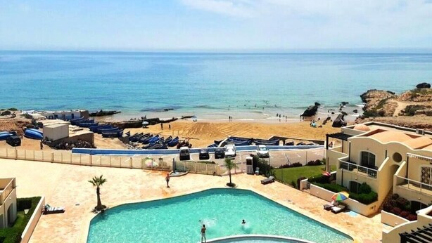 Ein Poolbereich mit Blick auf Strand und Meer.