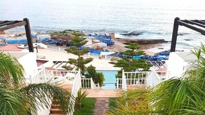 Blick auf einen Strandort mit Pool, Liegestühlen und Booten.