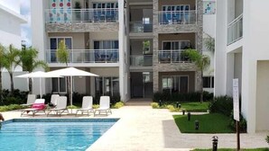 A modern building with a pool, multiple balconies, and a well-maintained lawn. - Close to the Beach! (Punta Cana)