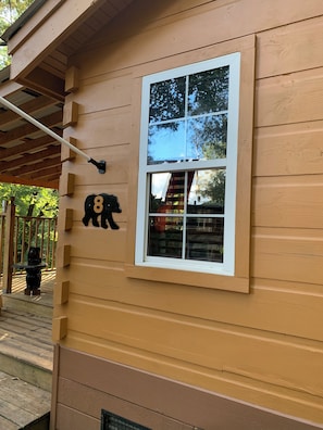 A wooden house with a large window, a black bear cutout, and a number '8' on the wall.