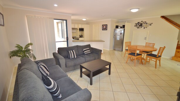 A living room with a grey sofa set, a coffee table, and a dining area with wooden chairs and a table.