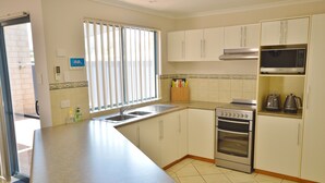 A kitchen with a built-in oven, microwave, and a window with blinds.