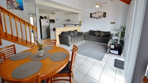 En rummelig opholdsstue med spisebord, sofaer og et køkken i baggrunden.