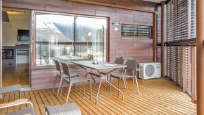 Un área de comedor al aire libre moderna con terraza de madera, sillas de metal y una mesa.