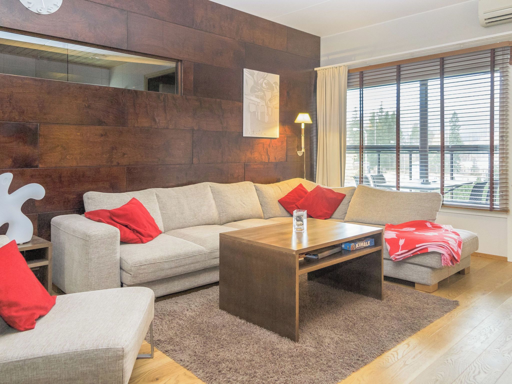 A modern living room with a sectional sofa, a coffee table, and a large window with blinds.