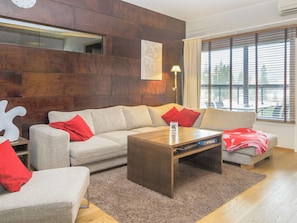 A modern living room with a sectional sofa, a coffee table, and a large window with blinds.