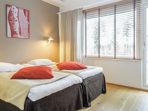 Ein Zimmer mit zwei Betten, einem Fenster mit Jalousien, einer Wandleuchte und einem Kunstwerk.