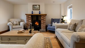 Una sala de estar acogedora con chimenea, dos sofás, una mesita de centro y una estantería.