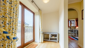 Um quarto com piso de madeira, um banco e uma porta com tapete de boas-vindas.