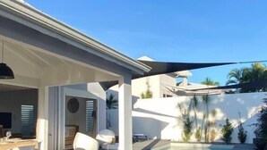 A modern outdoor pool area with lounge chairs and a dining setup. - Villa Pacha, Villa Pacha - Le Gosier (Le Gosier)