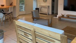 A spacious living area with a wooden bench, a TV, and a dining area with chairs and a table. - Villa Pacha, Villa Pacha - Le Gosier (Le Gosier)