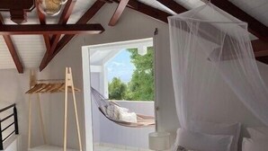 A bedroom with a bed, a hammock, a wooden ladder, and a view of the outdoors. - Villa Pacha, Villa Pacha - Le Gosier (Le Gosier)