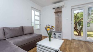 Ein modernes Wohnzimmer mit einem grauen Sofa, einem weißen Couchtisch mit Blumenvase und einer Schiebetür zu einem Garten.