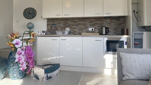 Une cuisine moderne avec des meubles blancs, un mur de fond en briques et une machine à café.