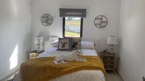 Une chambre à coucher avec un lit, une fenêtre, une table de chevet et une lampe.