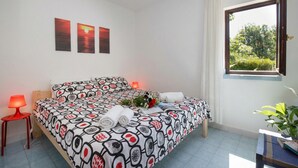 A bedroom with a bed, a nightstand, a window with curtains, and wall art.