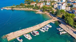 A coastal town with a marina, buildings with balconies, and a clear view of the sea.