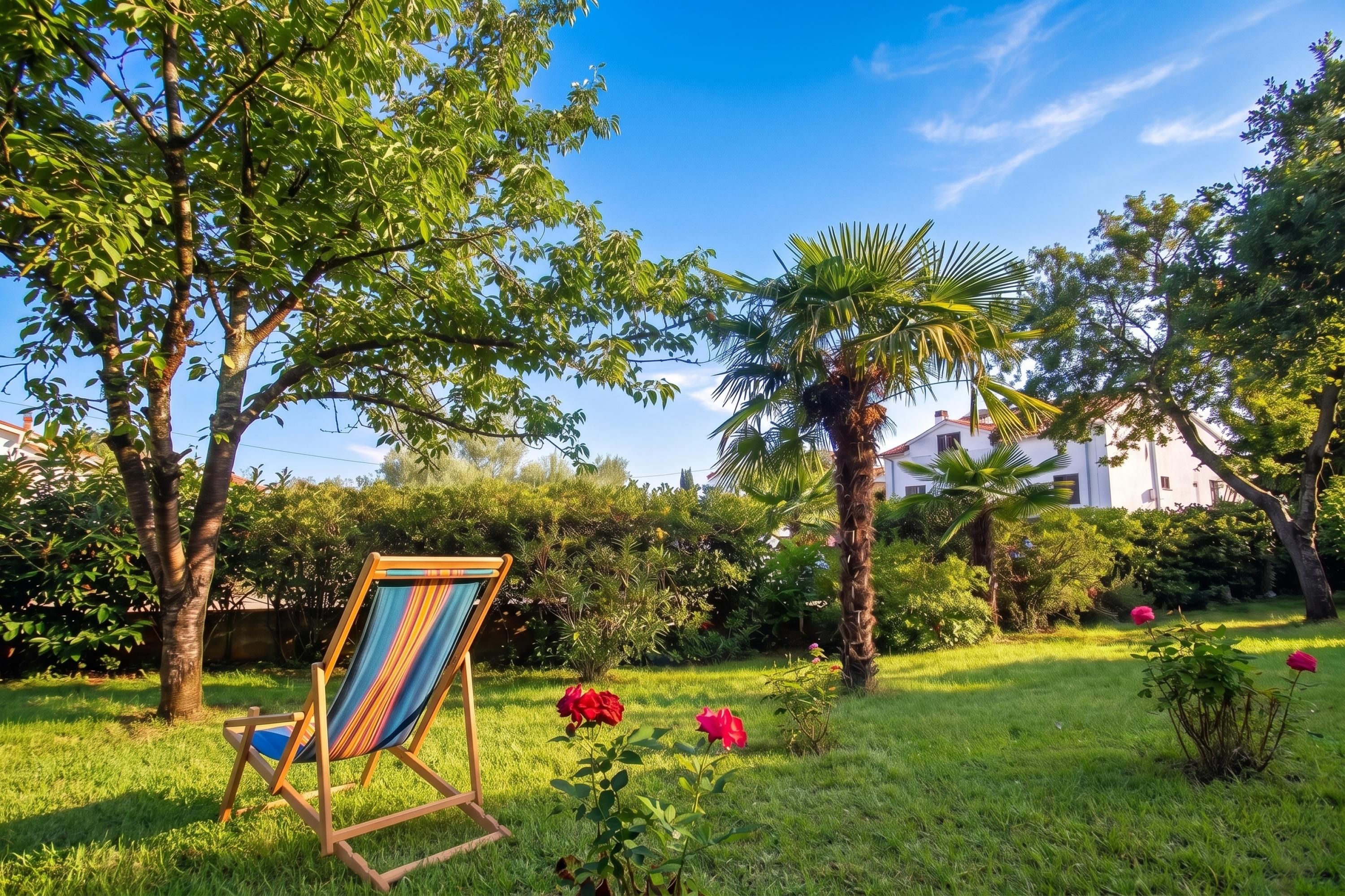 A garden with a hammock chair, palm trees, and red flowers.