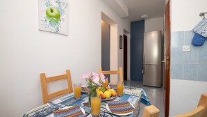 A dining area with a table set for two, a refrigerator, and a blue tiled wall.