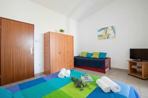 A room with a bed, a wardrobe, a television, and a painting on the wall.
