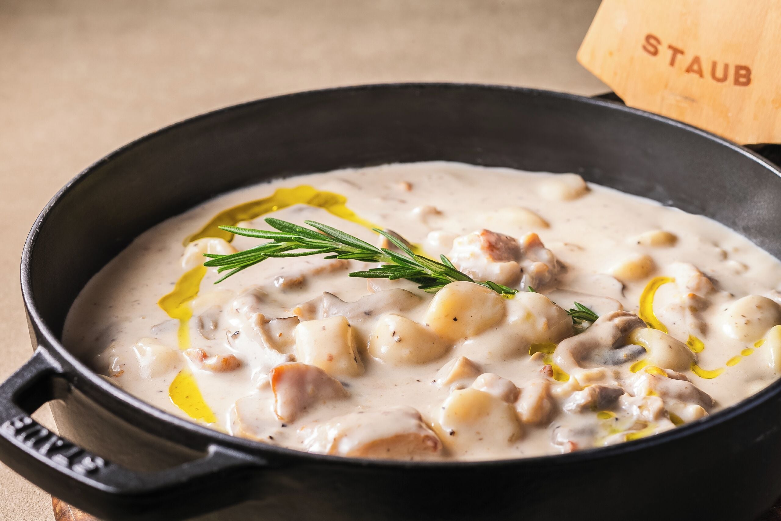 A close-up of a creamy soup with mushrooms and herbs in a black skillet.