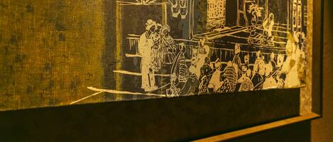 A framed artwork depicting a historical scene with figures and machinery.