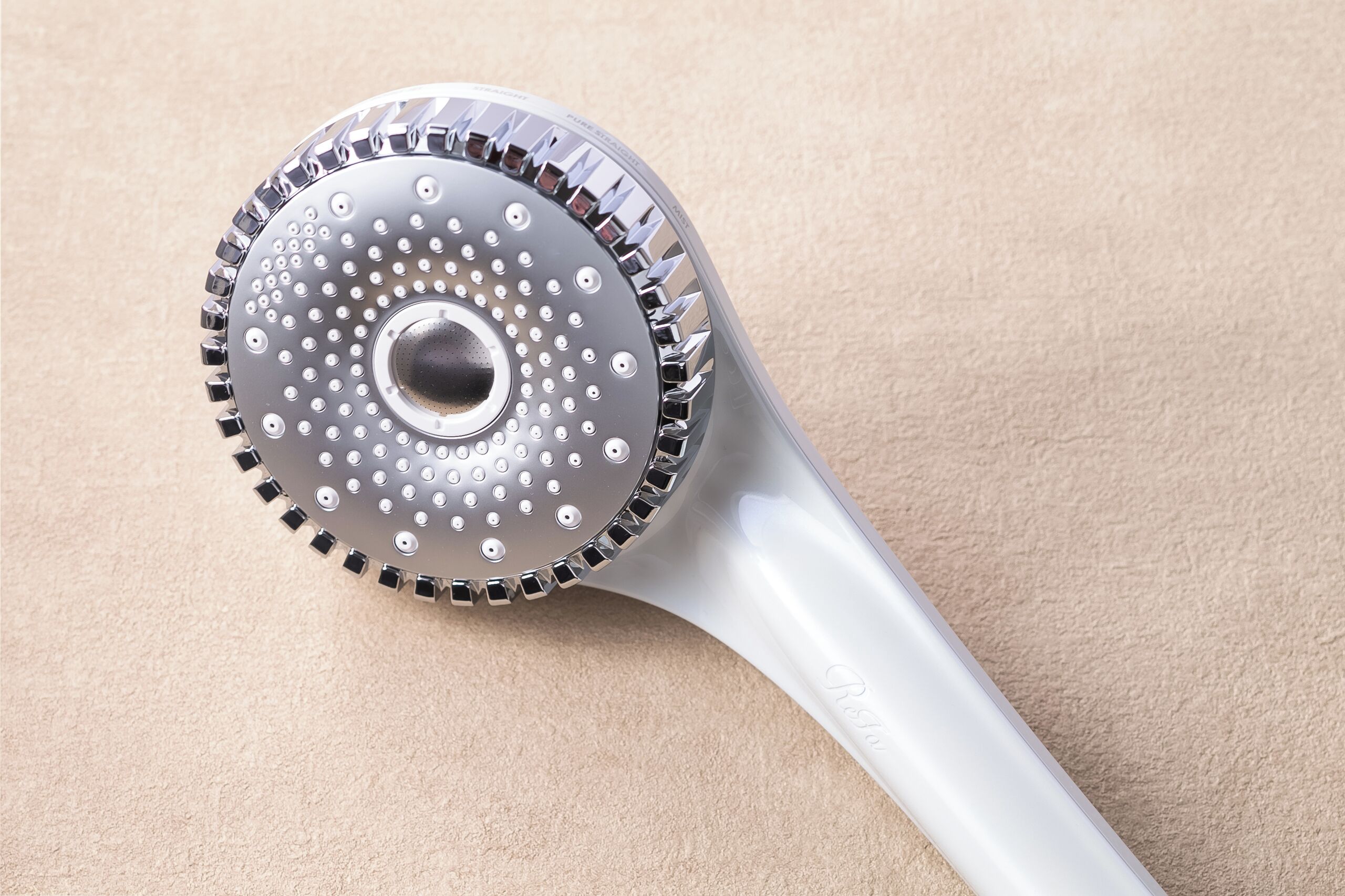 A metallic object with a circular pattern and a handle, placed on a textured surface.