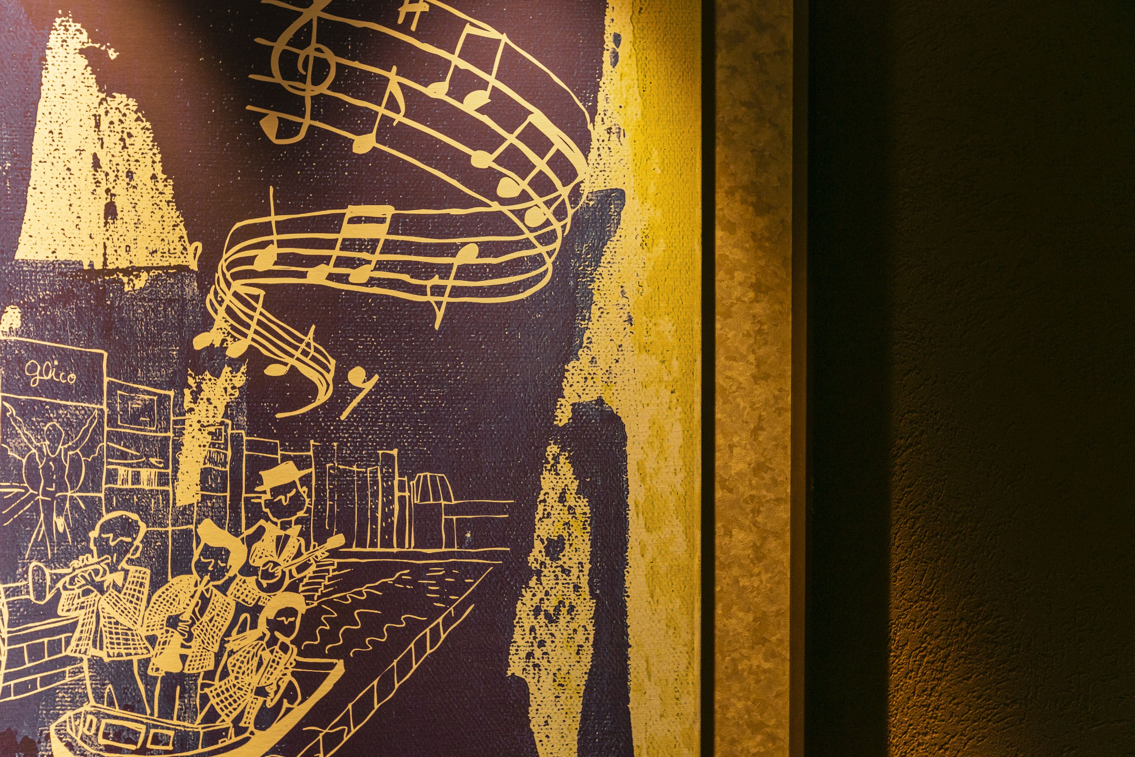 A wall with a yellow and black abstract design, featuring musical notes and figures.