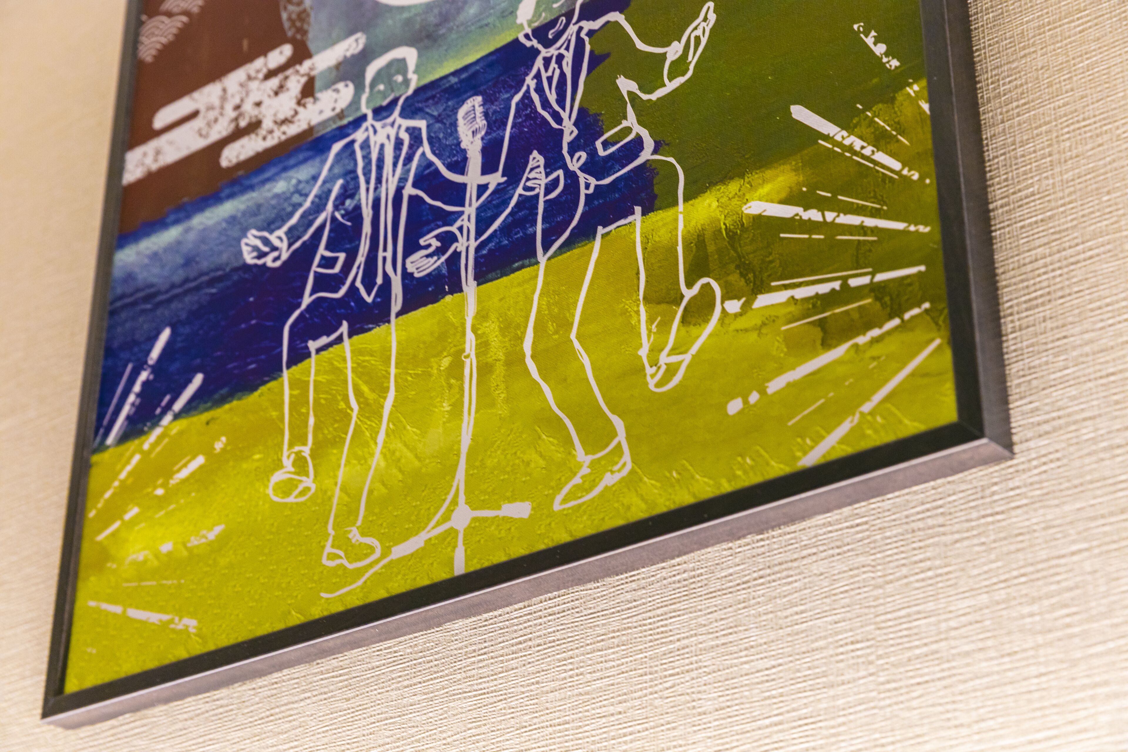 A framed artwork with abstract figures and a blue and yellow background.