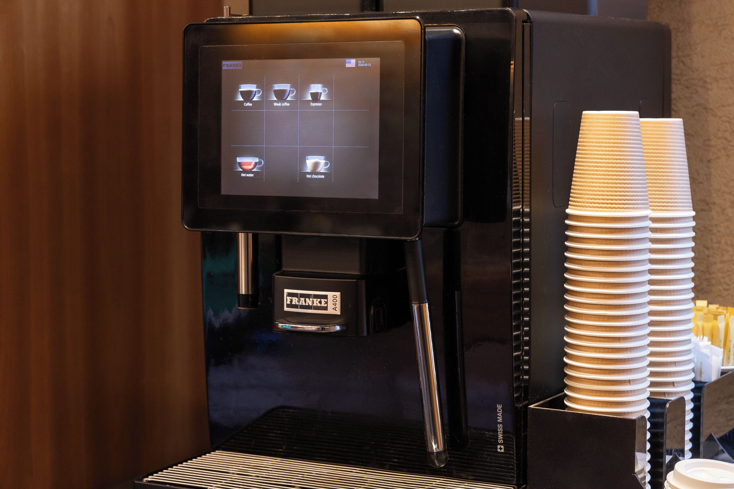 A coffee machine with a digital display, a branded coffee cup holder, and a branded coffee machine.