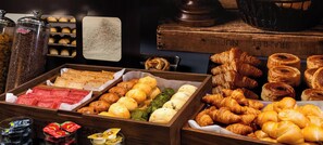 A variety of baked goods including bread, pastries, and croissants displayed in wooden trays.