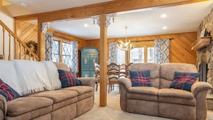 A cozy living room with two brown sofas, a wooden staircase, and a stone fireplace. - CPE1-Lovely Chalet! A/C, Pets Ok! (Davis)