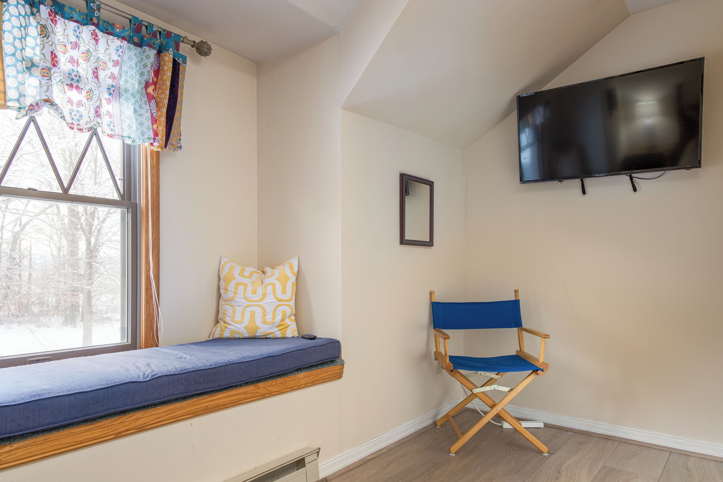 Ein Zimmer mit Fensterbank, Fernseher und Regiestuhl.